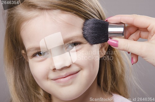 Image of Makeup artist deals powder on face of girl