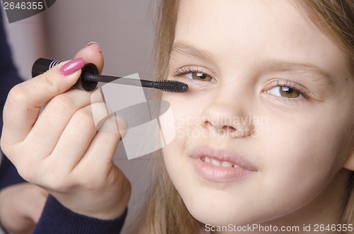 Image of Makeup artist paints eyelashes on girl's face