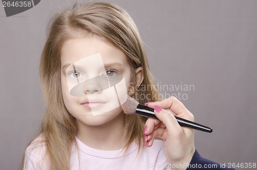 Image of Makeup artist deals powder on face of girl