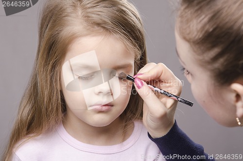 Image of Makeup artist paints eyelids on girl's face