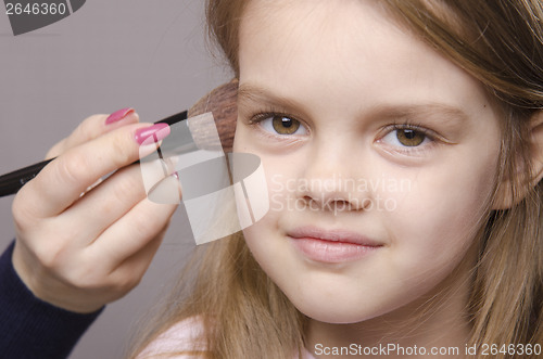 Image of Makeup artist deals powder on face of girl