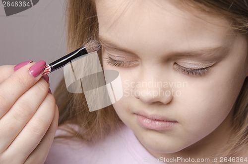 Image of Makeup artist paints eyelids on girl's face