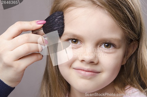 Image of Makeup artist deals powder on face of girl