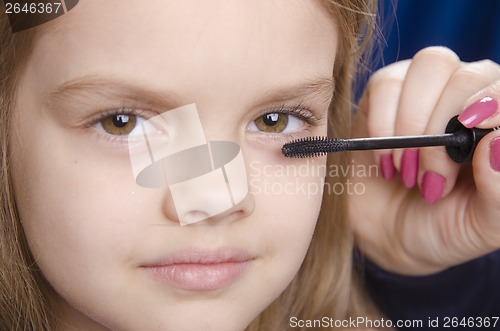 Image of Makeup artist paints eyelashes on girl's face