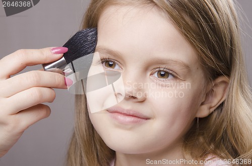 Image of Makeup artist deals powder on face of girl