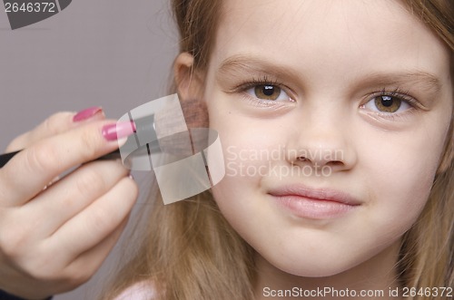 Image of Makeup artist deals powder on face of girl