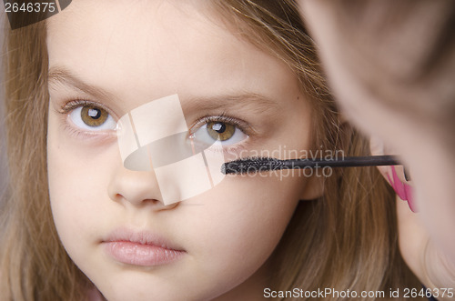 Image of Makeup artist paints eyelashes on girl's face
