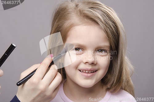Image of Makeup artist deals powder on face of girl