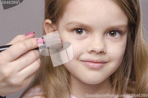 Image of Makeup artist deals powder on face of girl