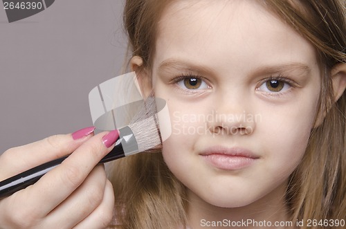 Image of Makeup artist deals powder on face of girl