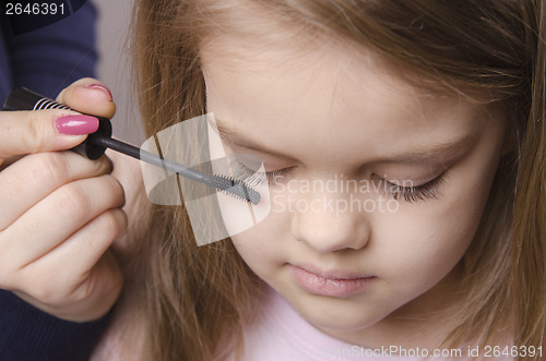 Image of Makeup artist paints eyelashes on girl's face