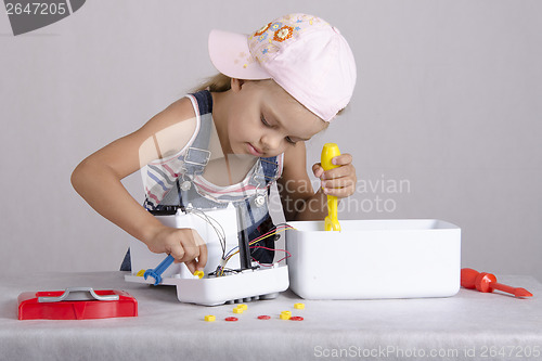 Image of Girl repairs toy small home appliances