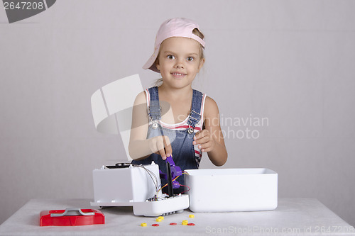 Image of Girl repairs toy small home appliances