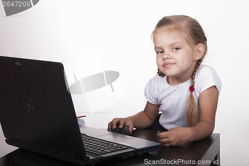 Image of girl sitting at table and quietly working behind notebook