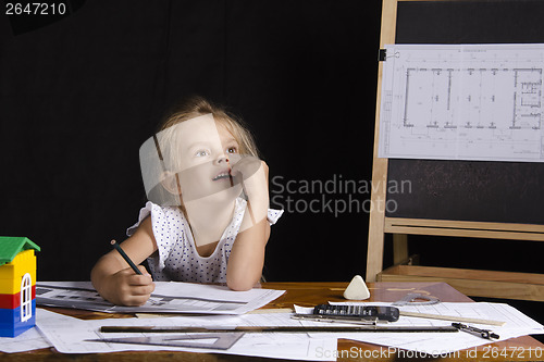 Image of Girl-architect sitting behind a Desk and thought dreamily