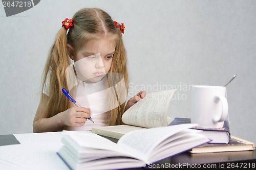 Image of Girl leafing through book and wrote on a sheet of paper abstract sitting