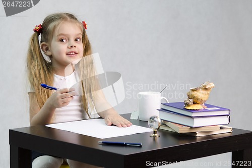 Image of girl happily looks in frame, sitting at table image of writer