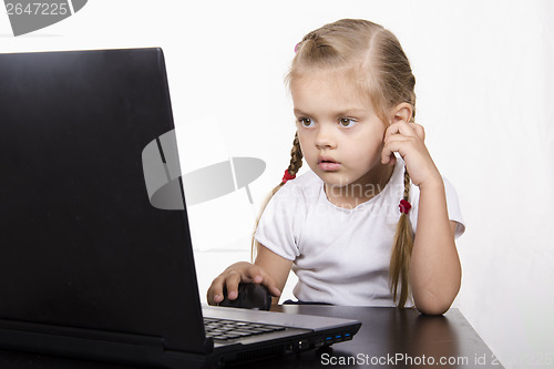 Image of girl sitting at table and quietly working behind notebook