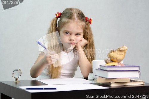 Image of girl writes on a piece of paper sitting at table in image writer