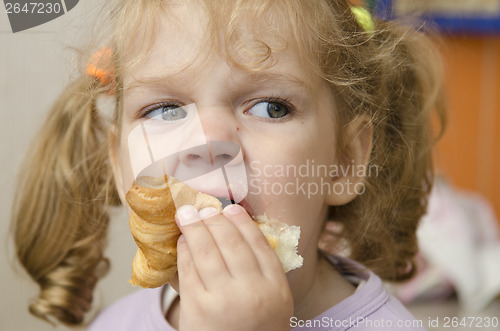 Image of little girl with enthusiasm and eats roll pleasure