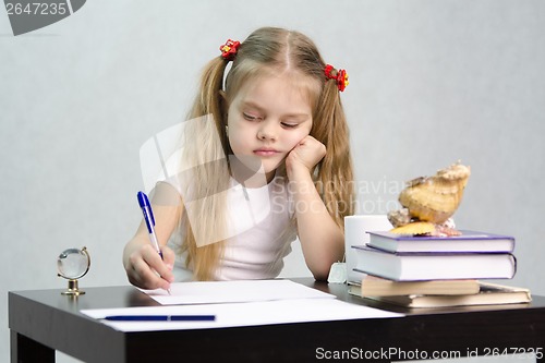 Image of girl writes on a piece of paper sitting at table in image writer