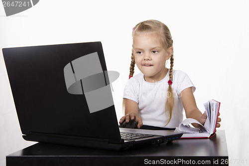 Image of girl working at laptop, and records in notebook