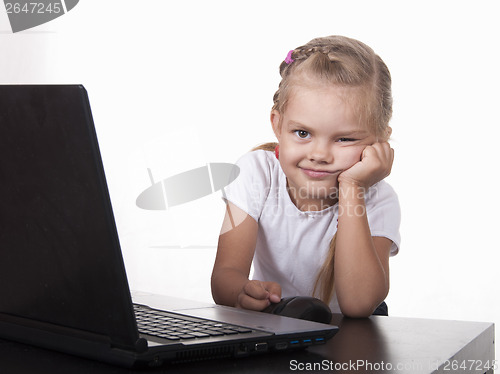 Image of girl sitting at table and quietly working behind notebook