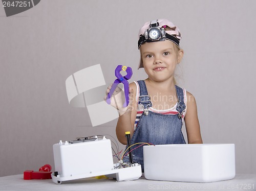 Image of Girl repairs toy small home appliances