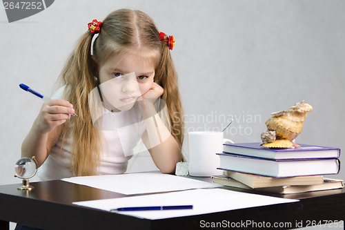 Image of girl writes on a piece of paper sitting at table in image writer
