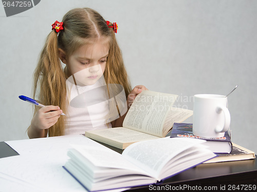 Image of Girl leafing through book and wrote on a sheet of paper abstract sitting