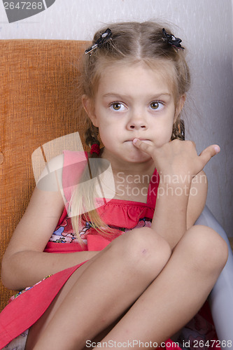 Image of Girl sitting on the couch and picks his nose