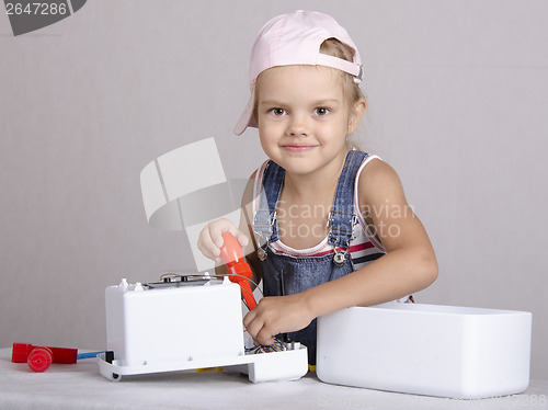 Image of Girl repairs screwdriver toy microwave