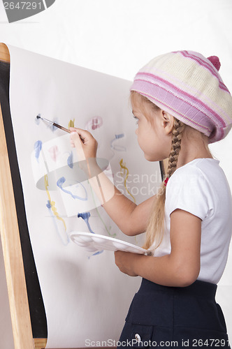 Image of The girl in image of artist draws on easel