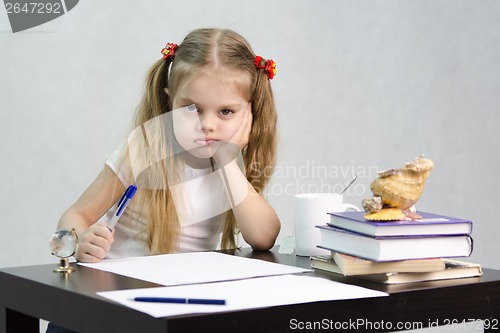 Image of girl writes on a piece of paper sitting at table in image writer