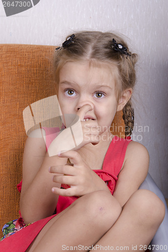 Image of Girl sitting on the couch and picks his nose