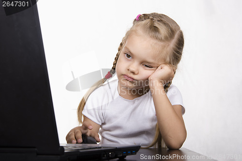 Image of girl sitting at table and quietly working behind notebook