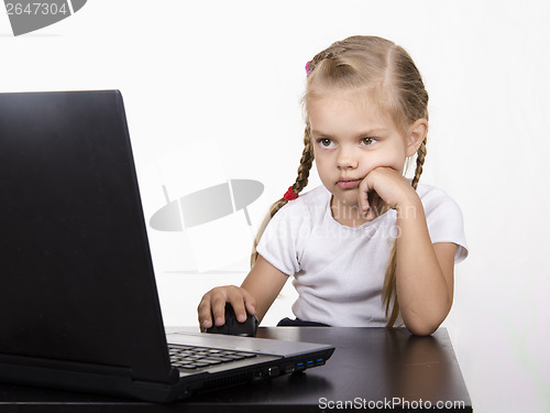 Image of girl sitting at table and quietly working behind notebook