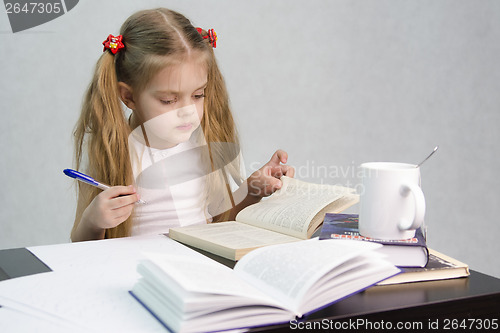 Image of Girl leafing through book and wrote on a sheet of paper abstract sitting