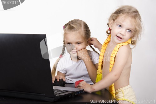 Image of girl working at laptop. Another approached her and took