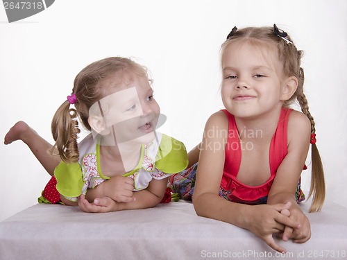 Image of Two girls lie, one tongue, the other smiles