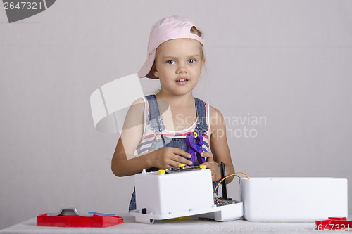Image of Girl repairs toy small home appliances