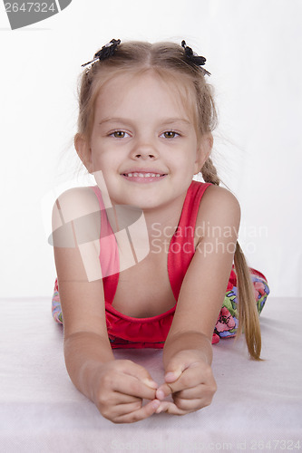 Image of girl is leaning on his hands and looks into frame