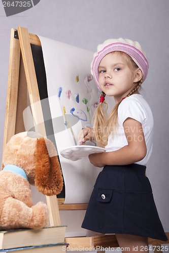 Image of The girl in image of artist draws on easel