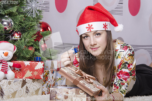 Image of Girl disappointed little gift, lying near Christmas tree