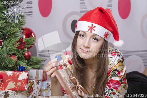 Image of Girl disappointed little gift, lying near Christmas tree