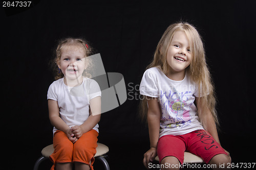 Image of Portrait of two young girls sitting on chairs