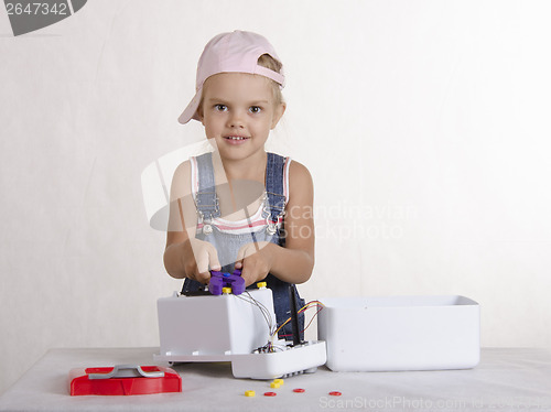 Image of Girl twists nut pliers, repairing toy