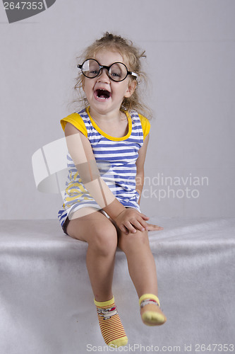 Image of Two-year-old girl in funny glasses sits and laughs cheerfully