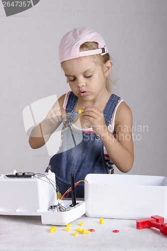 Image of Girl tighten screws to screw wrench, repairing toy