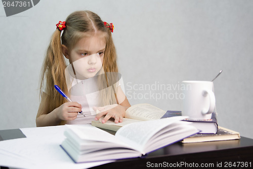 Image of Girl leafing through book and wrote on a sheet of paper abstract sitting